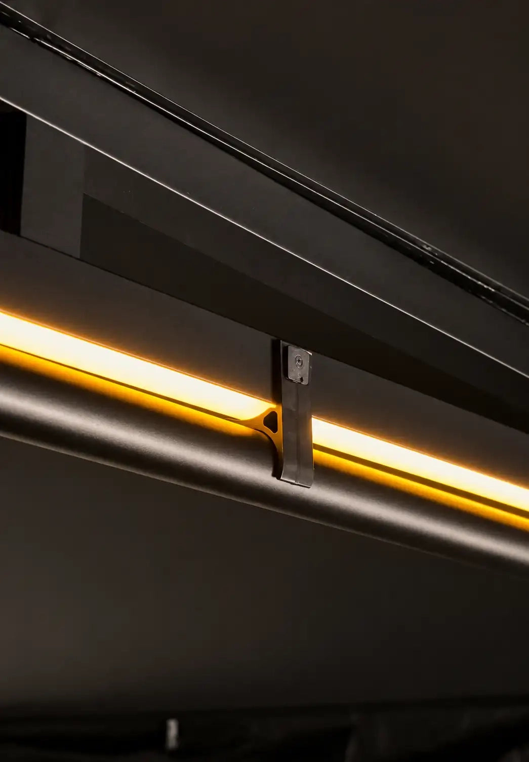 A close-up of a modern linear LED light bar with a warm yellow glow, built in inside the aluminum frame for the Awning with a clamp for telescopic pole.