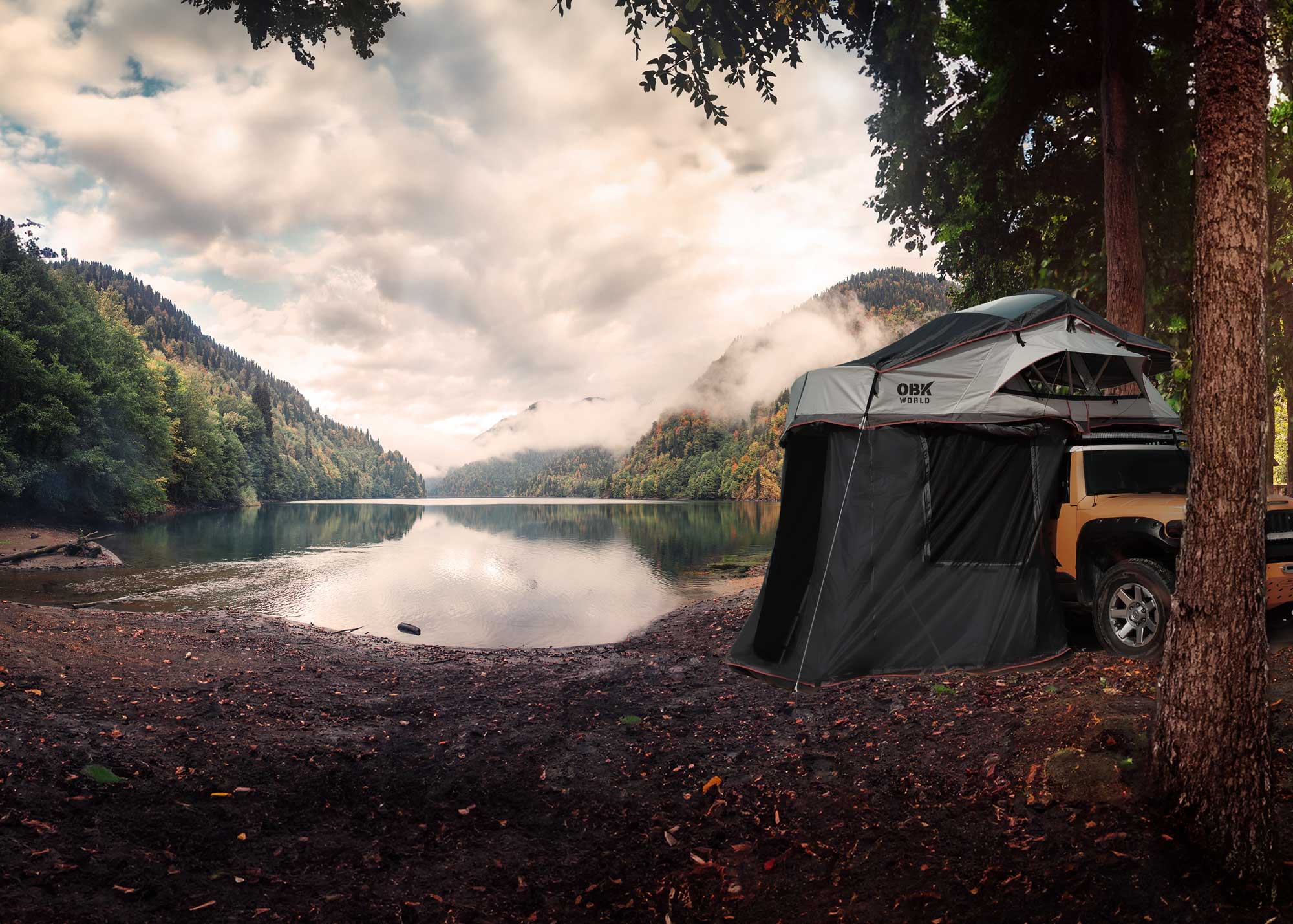 OBK rooftop tent with full annex mounted on an off-road SUV at a scenic lakeside campsite, creating a spacious enclosed shelter for comfortable outdoor camping.